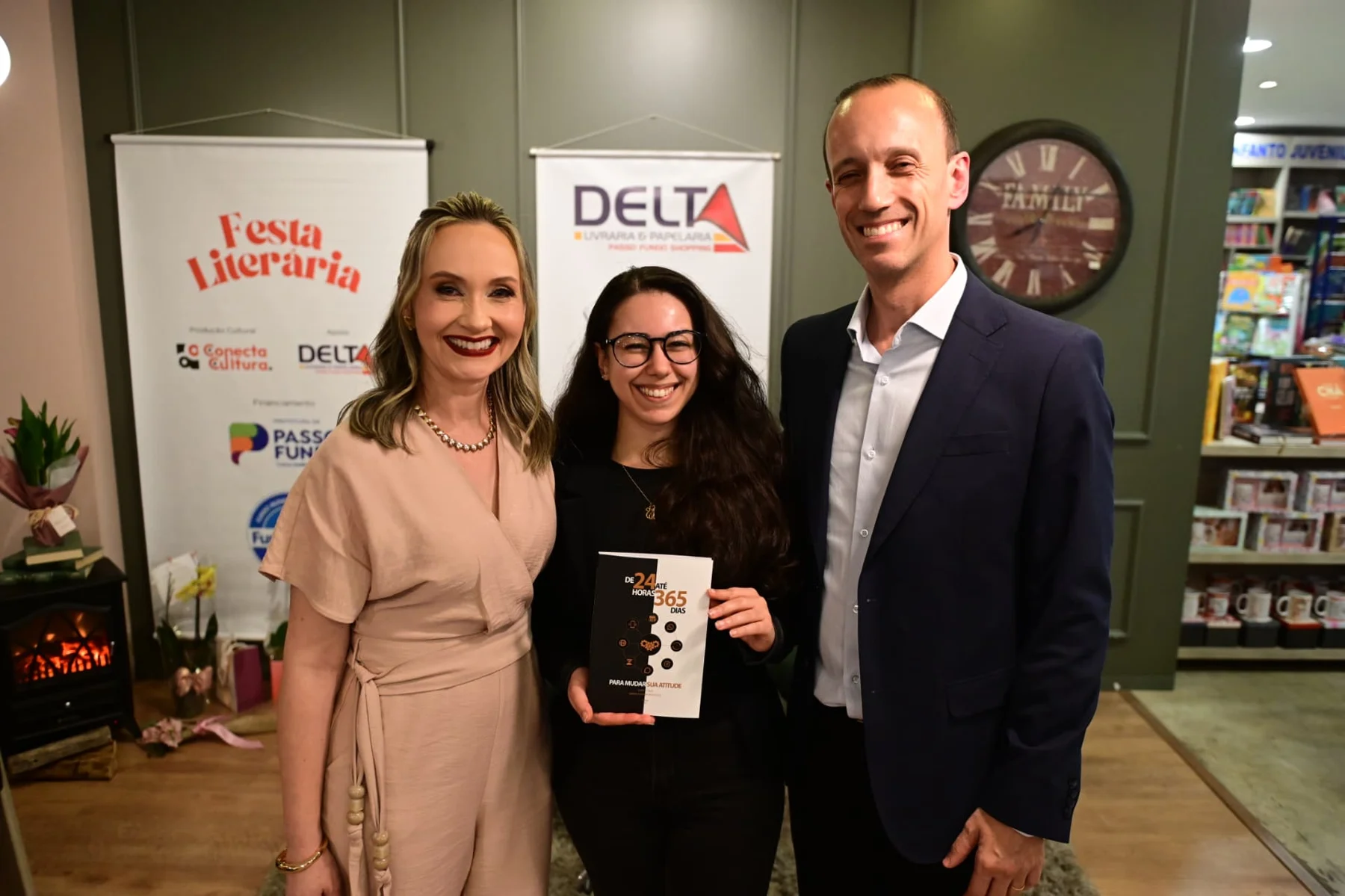 Graciela e Gabriel com uma leitora sorrindo e segurando o livro